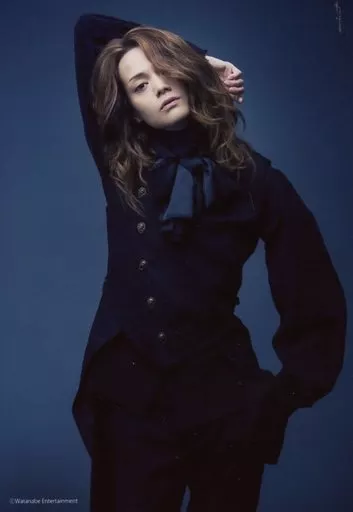 三浦涼介(ゲルハルト・フラ)/膝上・衣装黒・右手上げ・首傾げ・背景青/舞台「グランギニョル」ブロマイド