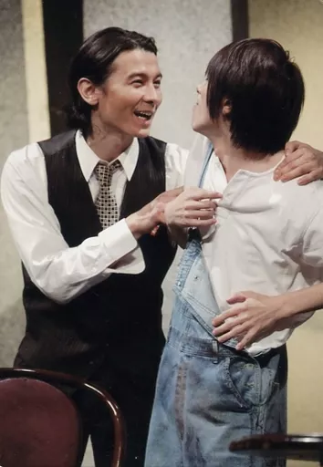 鈴木拡樹・藤田玲/ライブフォト・膝上・衣装白・黒・青・デニム・藤田左手鈴木肩・向き合い/舞台「愛が殺せとささやいた」公演ブロマイド