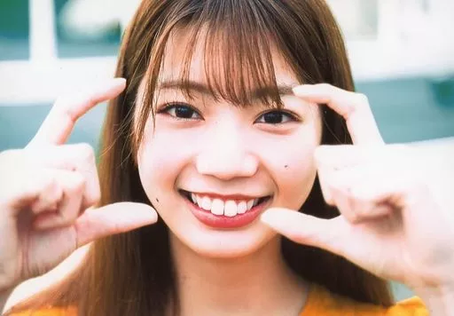 高本彩花/横型・顔アップ・衣装オレンジ・両手親指人差し指立て/日向坂46 ファースト写真集「立ち漕ぎ」発売記念ブロマイド