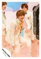 Hey! Say! JUMP/有岡大貴/膝上・衣装クリーム色・水色ピンク黄・ネクタイ黄・体右向き・左足上げ・笑顔・後ろに伊野尾薮/「キミアトラクション」PV＆ジャケ写撮影オフショット/公式生写真
